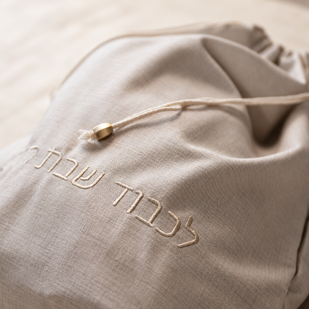Close-up of abstract tonal Linen & Loaf bread bag embroidery and gold hardware
